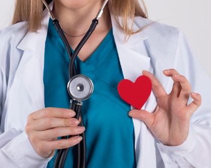 Consultatii cardiologice - medic cu stetoscop ce tine in mana o forma de inima