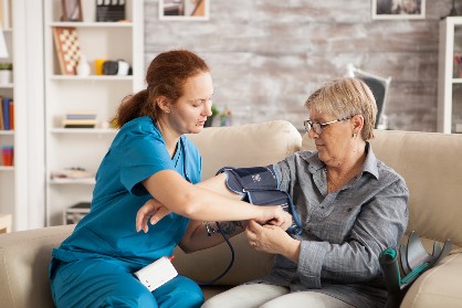 Servicii de infirmerie - asistent care ii ia tensiunea acasa unui pacient 